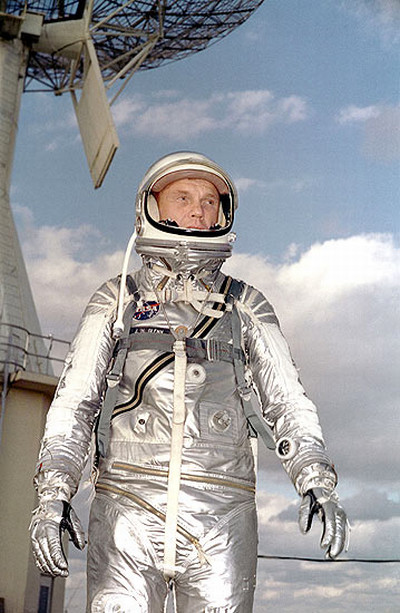 Ahora un astronauta con un traje plateado con rayas azules casco con amplio visor guantes 